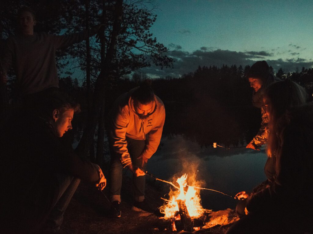 Group of friends sitting in front of a bonfire. Photo by Elias Strale